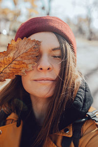 Stylish young brunette woman in maroon knitted hat,  jacket. unfiltered aesthetic atypical portrait