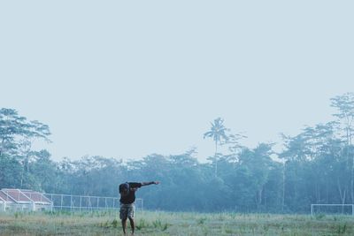 Full length of man standing on field against clear sky