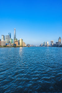 Sea by buildings against clear blue sky