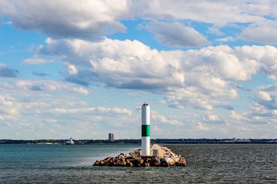 Lighthouse by sea against sky