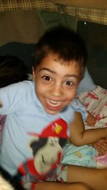 Portrait of smiling boy on bed at home