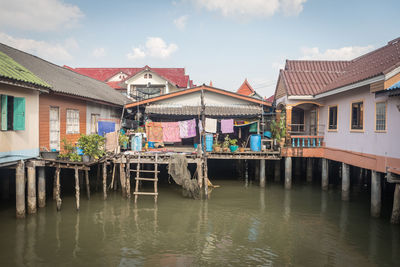 Houses in river by buildings against sky