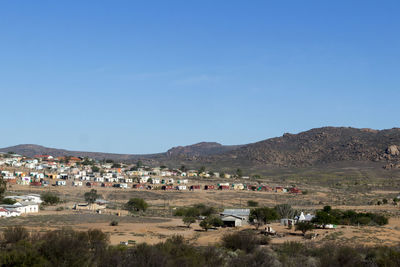 Town by mountains against clear blue sky