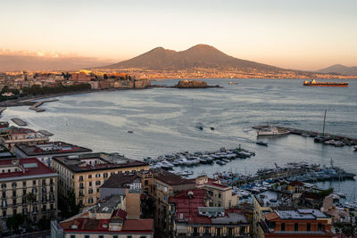 High angle view of townscape by sea against sky during sunset