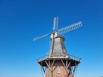 Low angle view of traditional windmill against clear blue sky