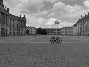 Bicycle on street by buildings against sky