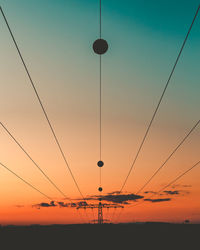 Silhouette power lines against sky during sunset