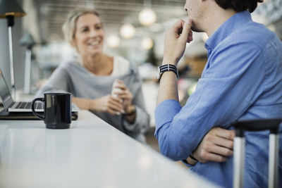 Midsection of businessman sitting with female colleague at airport cafe