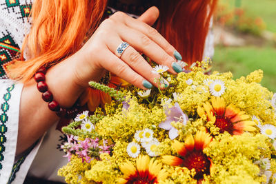 Midsection of woman holding flower bouquet while standing on grass