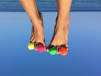 Low section of person with colorful balls against sea