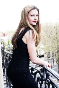 Portrait of beautiful woman against railing