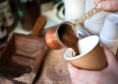 Cropped hands of person pouring coffee in cup