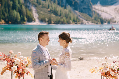 Rear view of couple standing by water at park