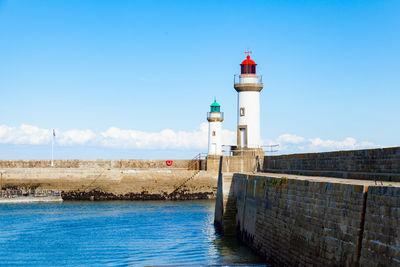 Lighthouse by sea against sky