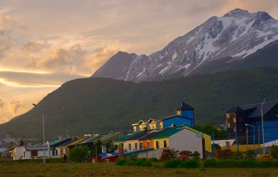 Houses by mountains against sky during sunset