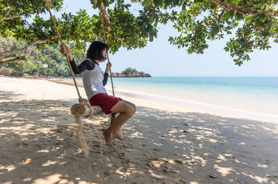 Rear view of woman sitting on beach