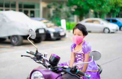 Cute girl wearing pollution mask sitting on motorcycle