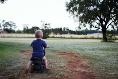 Rear view of boy sitting on land
