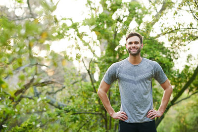 Portrait of young man standing against trees