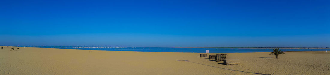 View of calm beach against clear blue sky