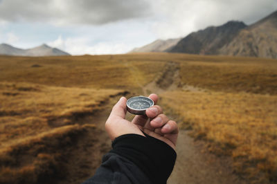 Cropped and of man holding compass against field