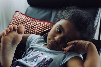 Close-up of bored girl lying on chair at home