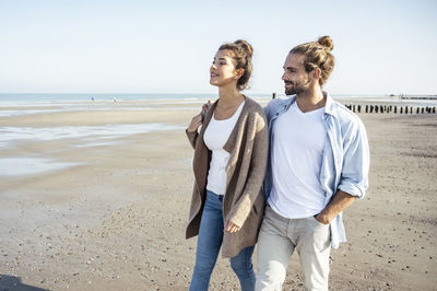 Friends enjoying at beach against sky