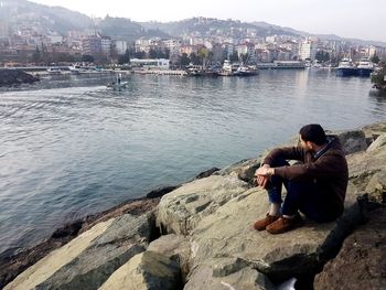 Men sitting on rock by water