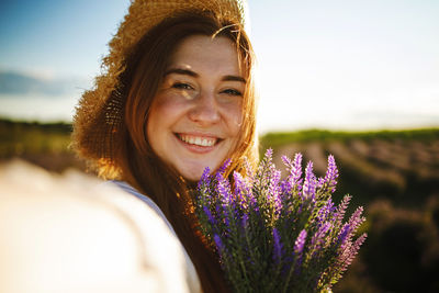 Portrait of young woman standing in lavender field taking selfie