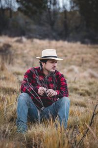 Full length of man wearing hat sitting on field