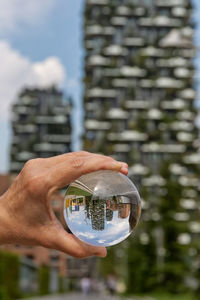 Cropped hand holding crystal ball with reflection on towers