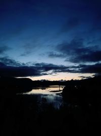 Scenic view of lake against dramatic sky during sunset