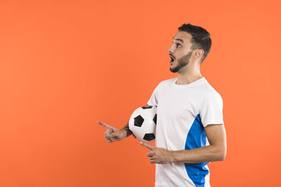 Young man with arms raised standing against yellow background