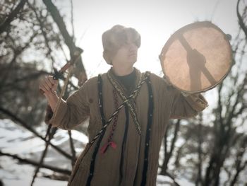 Man playing musical instrument against trees