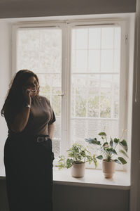 Smiling businesswoman talking on smart phone while standing near window at office