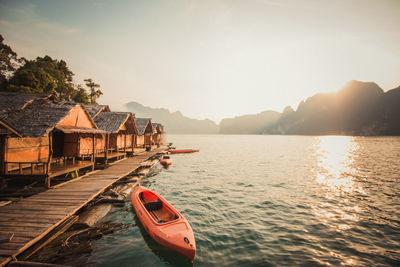 Canoe moored in lake during sunset