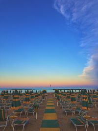 Empty chairs on beach against blue sky