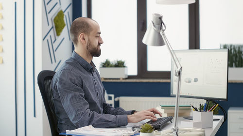 Side view of man working on computer