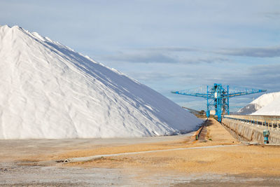 Large heap of salt and crane at factory