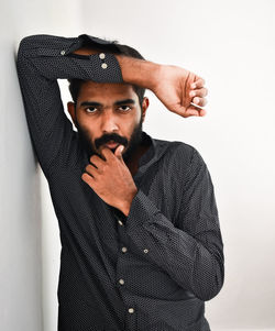 Portrait of young man standing against white background