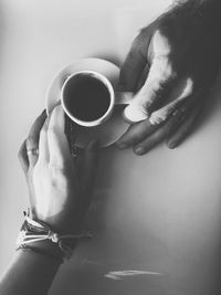 Cropped hands of couple holding coffee on table