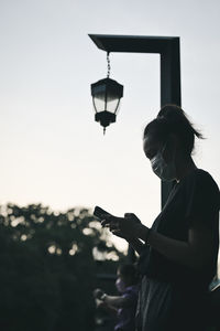 Golden hour, candid young woman on the bridge playing with her phone , hope and dream concept