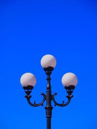 Low angle view of street light against blue sky