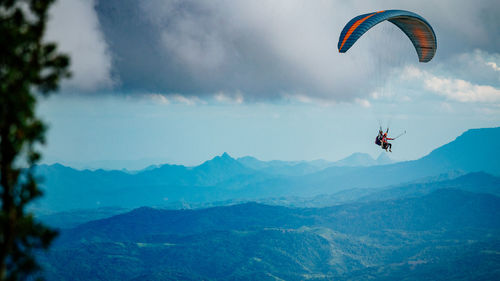 People paragliding over mountain against sky