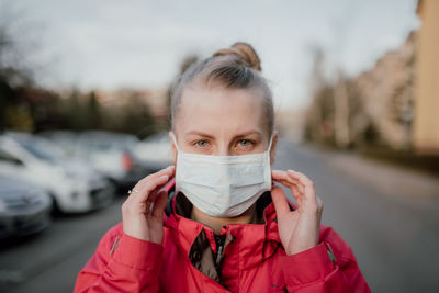 Portrait of woman wearing mask standing on road