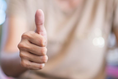 Midsection of person gesturing thumbs up