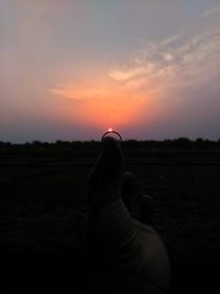 Midsection of person against sky during sunset