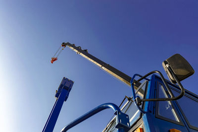 Low angle view of crane against clear blue sky