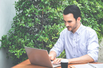 Young man using mobile phone while sitting on table