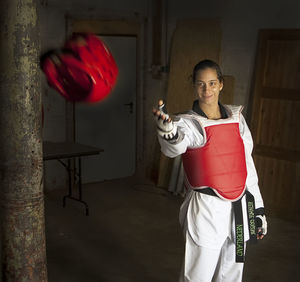 Smiling woman taekwondo athlete catching red head protector